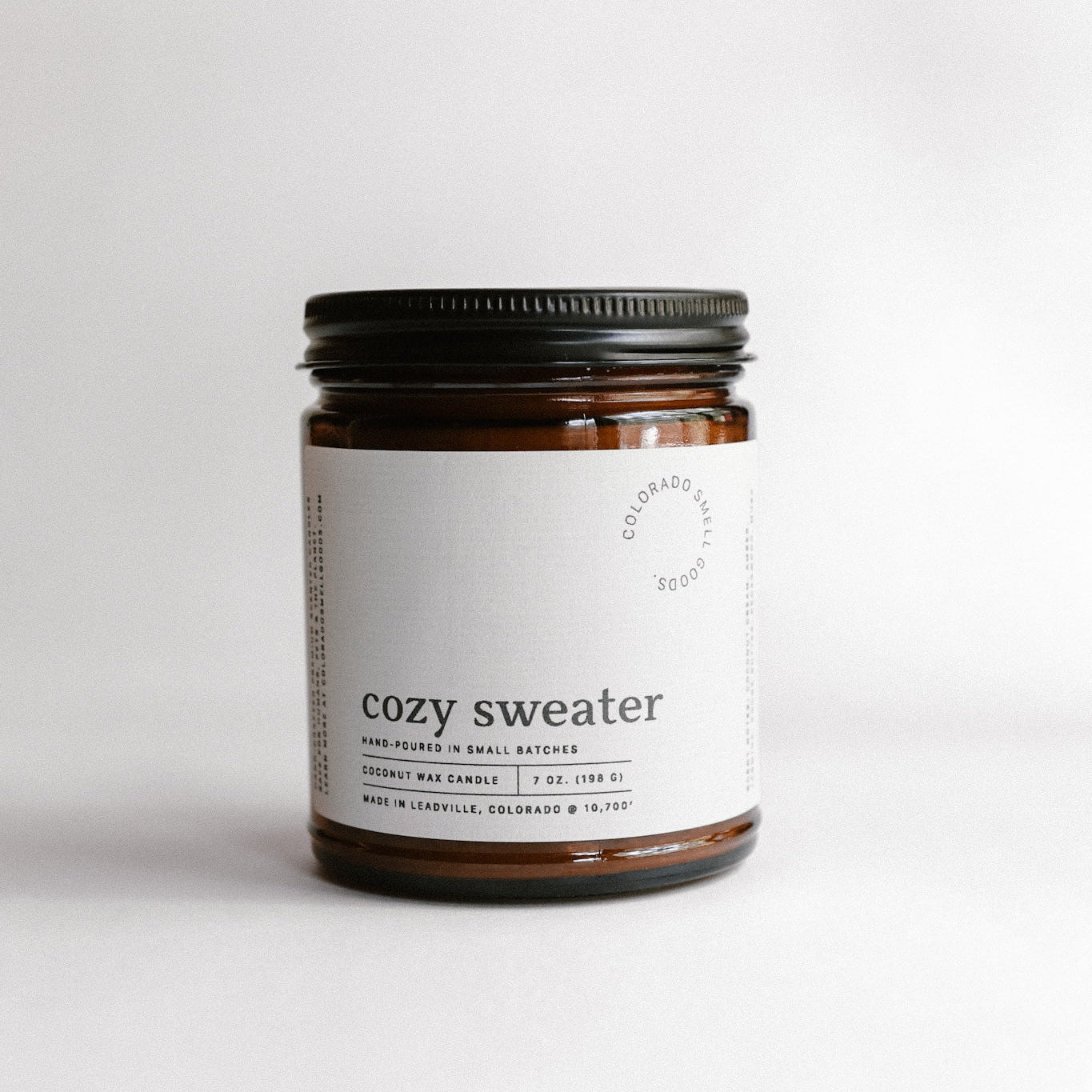 Candle jar labeled 'cozy sweater' on a white background